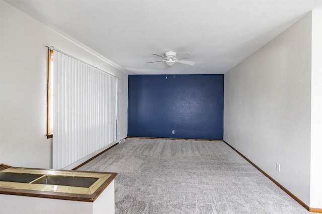 spare room with carpet flooring, ceiling fan, and baseboards