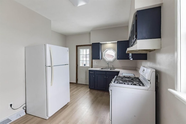 kitchen with white appliances, a sink, visible vents, light wood-style floors, and blue cabinetry