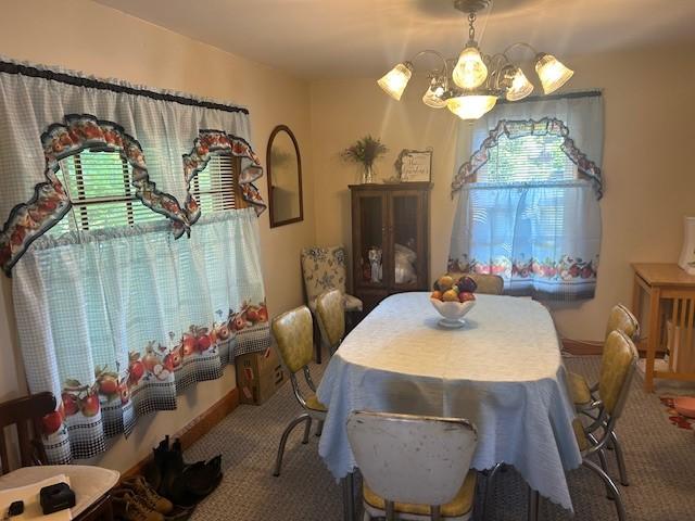 carpeted dining space with a chandelier