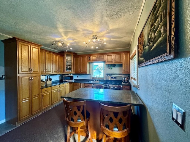 kitchen with a kitchen bar, a textured ceiling, stainless steel appliances, crown molding, and sink