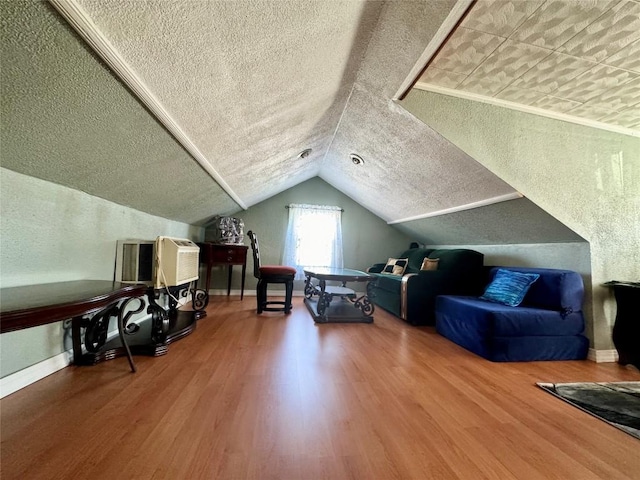 additional living space with wood-type flooring, a textured ceiling, and vaulted ceiling