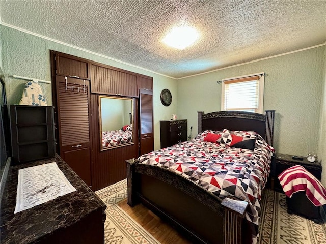 bedroom with a textured ceiling, light hardwood / wood-style floors, and crown molding