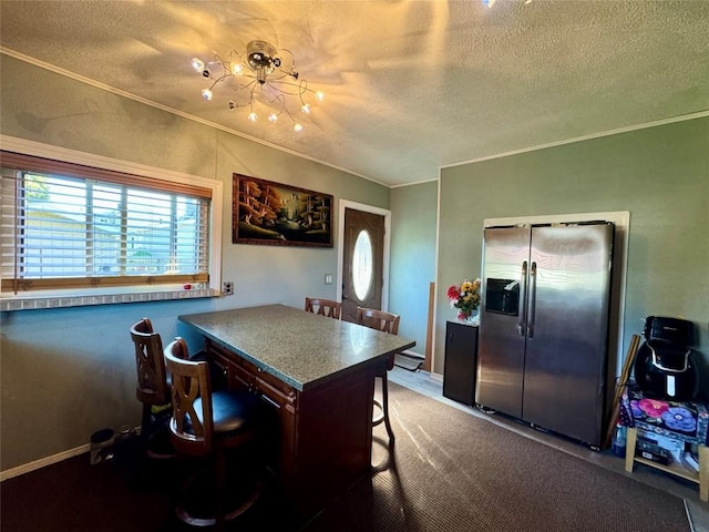 kitchen with a textured ceiling, a breakfast bar, and stainless steel refrigerator with ice dispenser