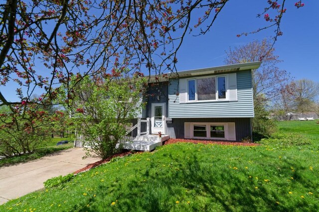 bi-level home with concrete driveway and a front lawn