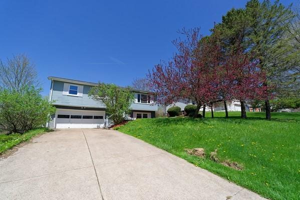 view of front of house featuring an attached garage, driveway, and a front lawn