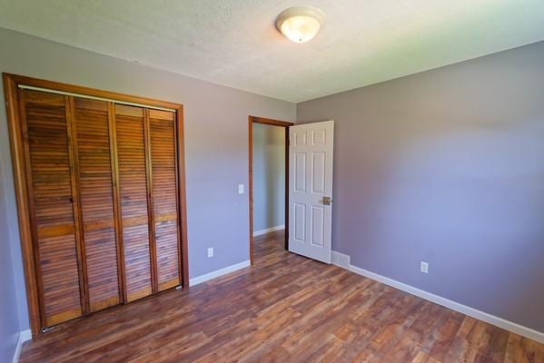 unfurnished bedroom featuring baseboards, a closet, and wood finished floors