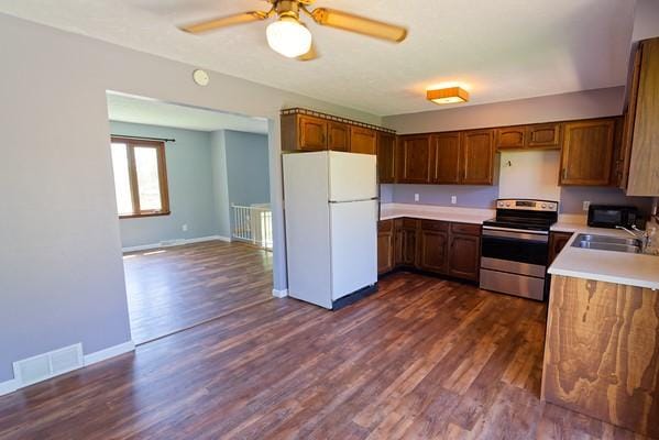 kitchen featuring visible vents, freestanding refrigerator, dark wood-style flooring, a sink, and stainless steel range with electric cooktop