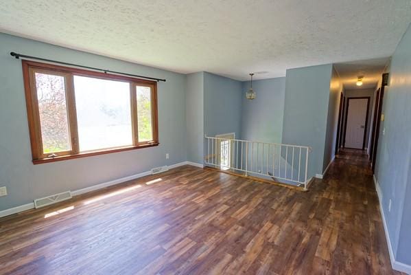 spare room with a textured ceiling, wood finished floors, and visible vents