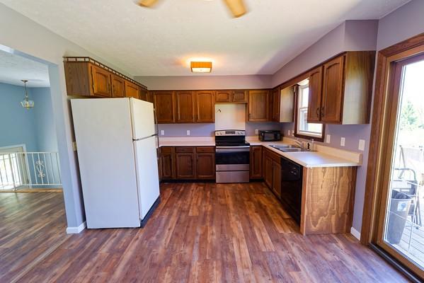 kitchen with light countertops, a sink, black appliances, and dark wood-type flooring