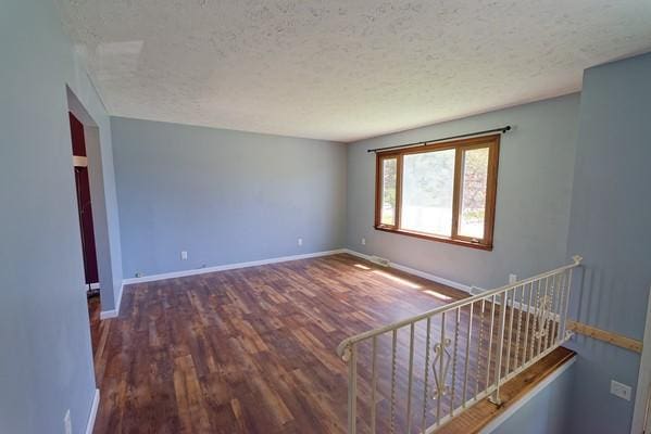 unfurnished room featuring baseboards, a textured ceiling, and wood finished floors