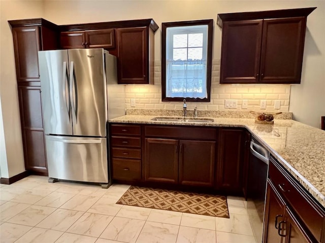 kitchen featuring backsplash, light stone countertops, appliances with stainless steel finishes, marble finish floor, and a sink