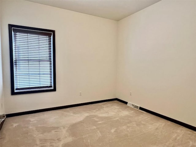 unfurnished room featuring visible vents, carpet floors, and baseboards