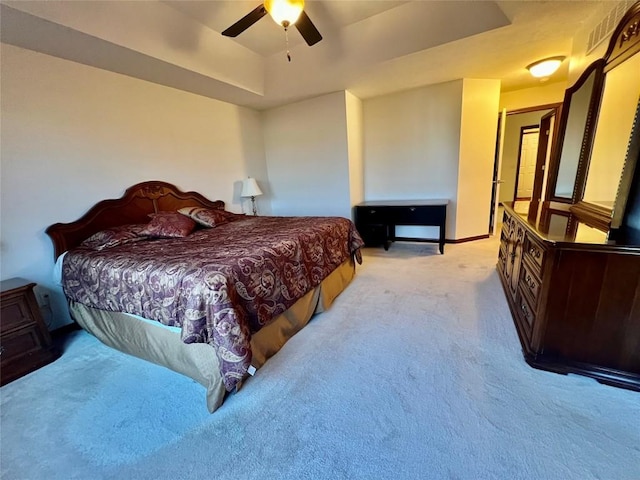 bedroom with ceiling fan, a tray ceiling, baseboards, and light carpet