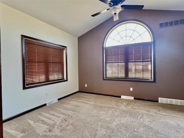 carpeted spare room featuring visible vents, lofted ceiling, and a ceiling fan