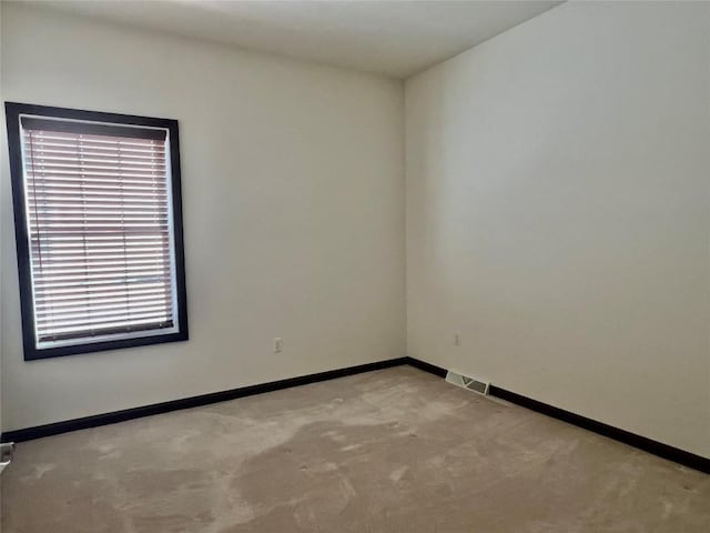 carpeted spare room featuring visible vents and baseboards