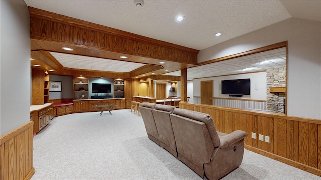 carpeted living room with built in shelves, a textured ceiling, and wood walls