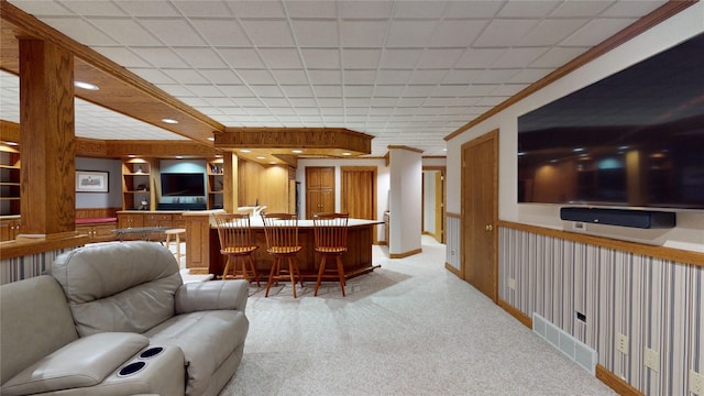 carpeted living room featuring bar area, built in shelves, and crown molding