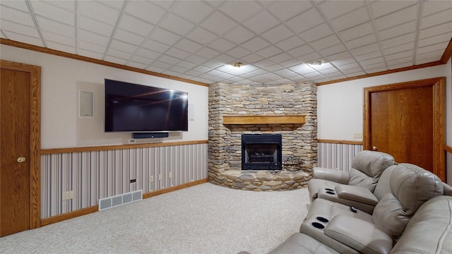 carpeted living room with a stone fireplace and ornamental molding