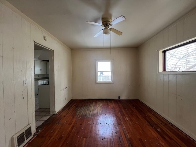 spare room featuring ceiling fan, wood walls, and dark hardwood / wood-style flooring