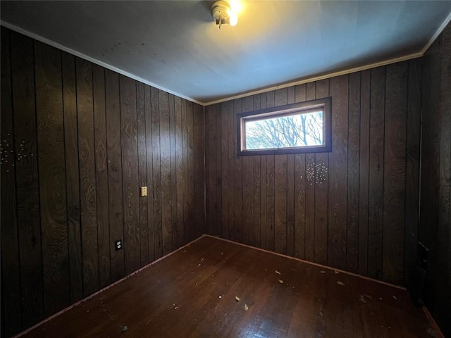 spare room featuring wood walls, ornamental molding, and dark wood-type flooring