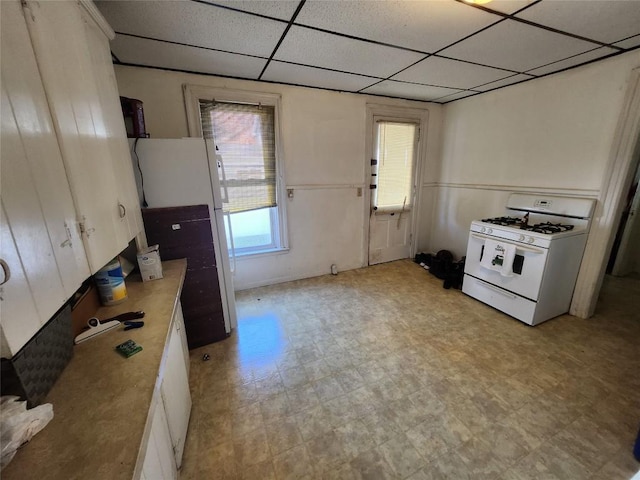 kitchen with white cabinets, white appliances, and a drop ceiling