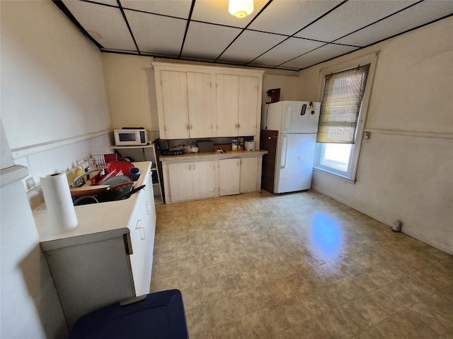 kitchen featuring a paneled ceiling, sink, white cabinets, and white appliances