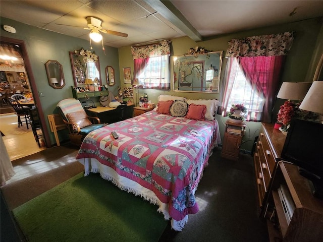 carpeted bedroom featuring beam ceiling and ceiling fan