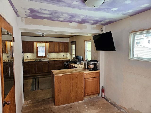 kitchen with a wealth of natural light, kitchen peninsula, sink, and backsplash