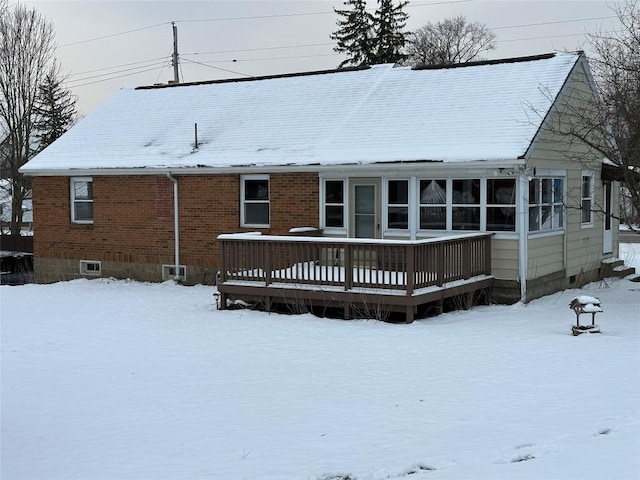 snow covered back of property featuring a deck