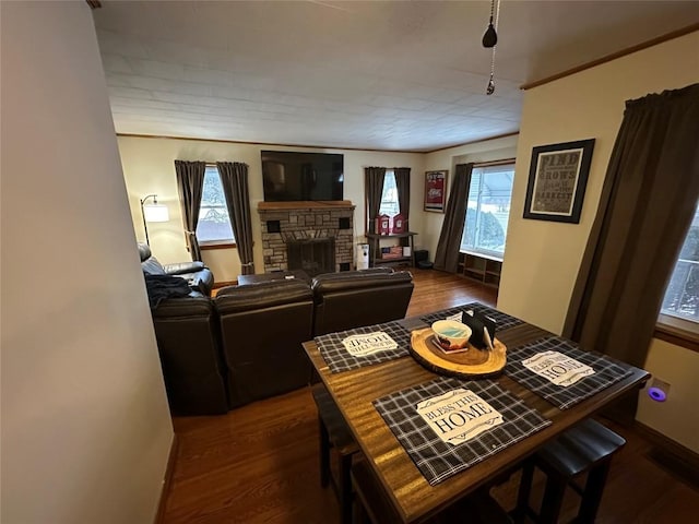 dining room with a stone fireplace and dark wood-type flooring