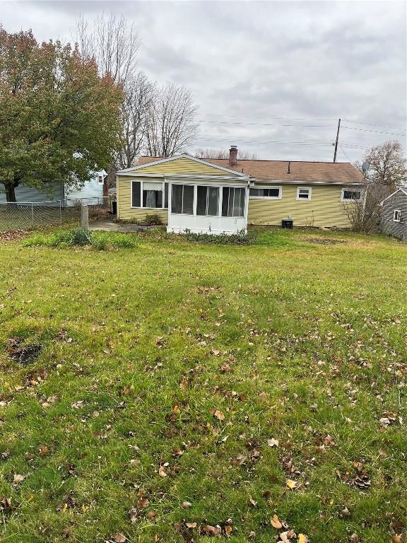 back of property featuring a lawn and a sunroom