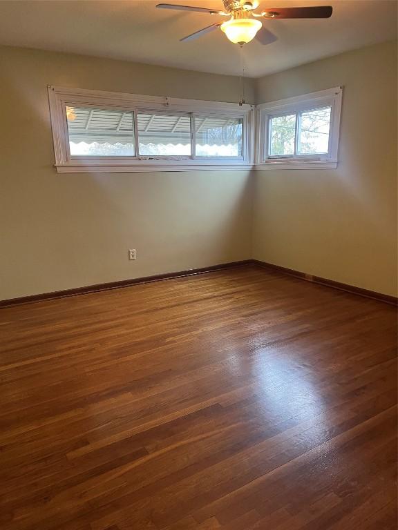 unfurnished room with ceiling fan, a healthy amount of sunlight, and dark wood-type flooring