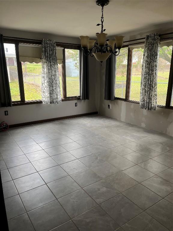 unfurnished dining area with a chandelier and light tile patterned flooring