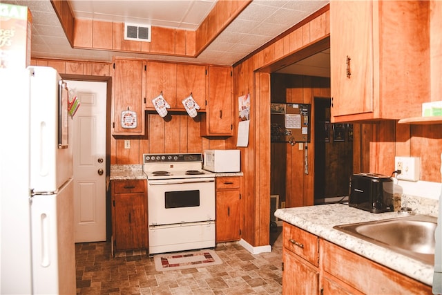 212 Main St, Jamestown, PA 16134 - kitchen with white appliances, light countertops, brown cabinetry, and wood walls