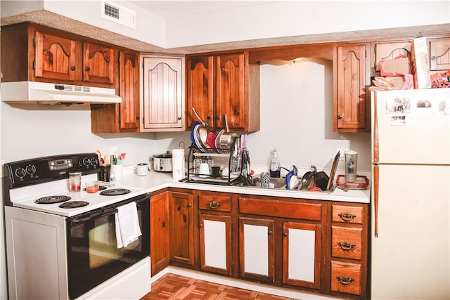 212 Main St, Jamestown, PA 16134 - kitchen with electric stove, freestanding refrigerator, under cabinet range hood, light countertops, and brown cabinets