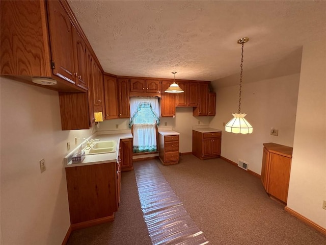 kitchen with sink, carpet floors, hanging light fixtures, and a textured ceiling