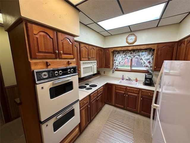 kitchen featuring white appliances, a paneled ceiling, and sink