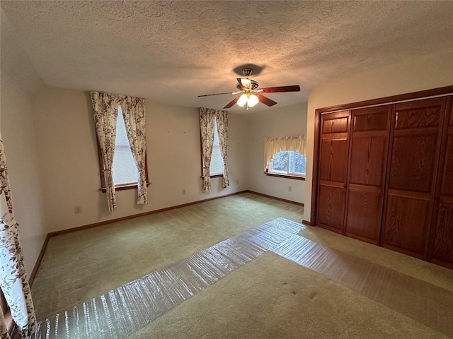 unfurnished bedroom with light carpet, a textured ceiling, a closet, and ceiling fan