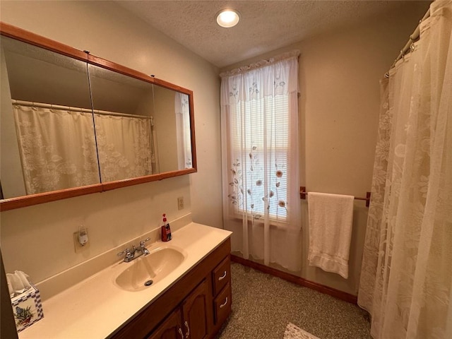 bathroom with curtained shower, vanity, and a textured ceiling