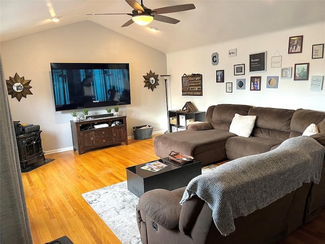 living room with a wood stove, ceiling fan, vaulted ceiling, and hardwood / wood-style flooring