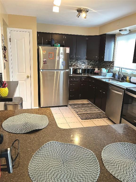 kitchen with decorative backsplash, light tile patterned flooring, sink, and stainless steel appliances