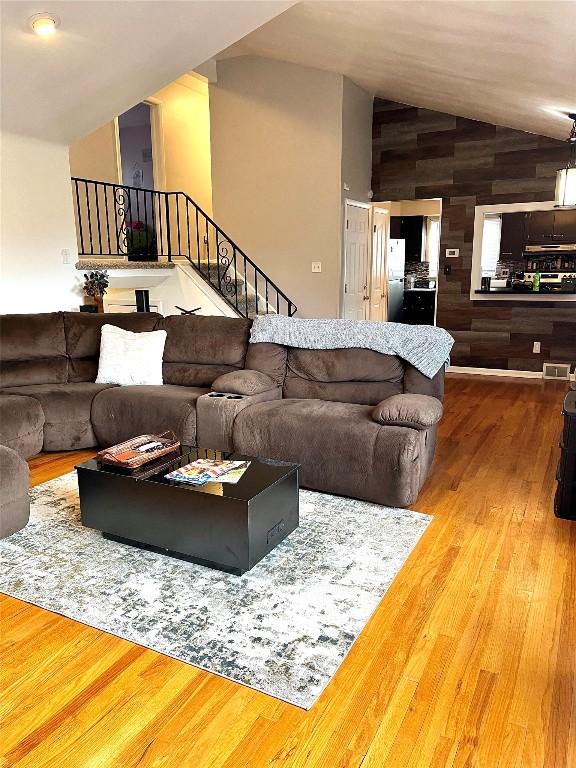 living room featuring lofted ceiling, wood walls, and wood-type flooring