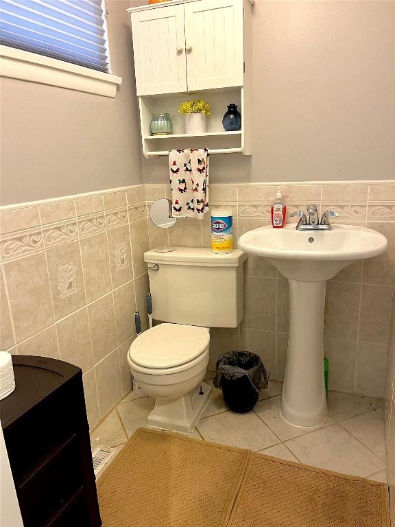 bathroom featuring tile patterned flooring, toilet, and tile walls