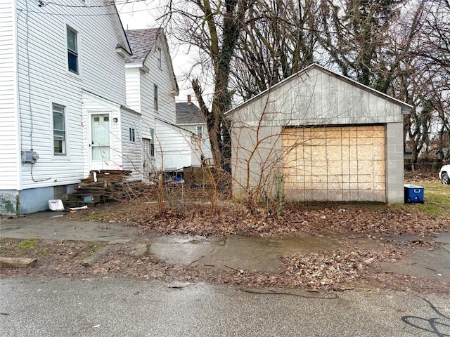 view of side of home featuring a shingled roof, entry steps, and an outdoor structure