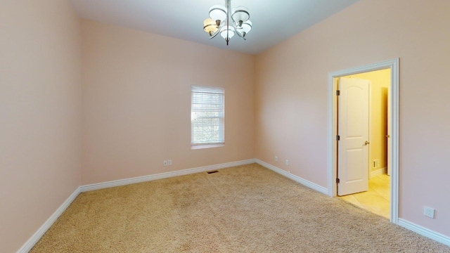 unfurnished room featuring a chandelier, light colored carpet, and baseboards