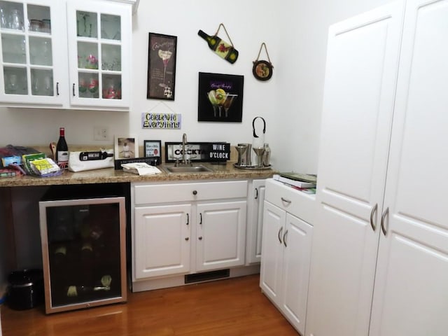 bar with white cabinetry, dark wood-type flooring, wine cooler, and dark stone counters