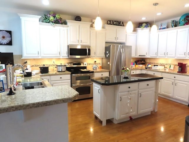 kitchen with sink, stainless steel appliances, pendant lighting, white cabinets, and light wood-type flooring