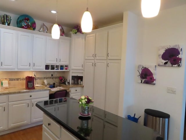 kitchen with tasteful backsplash, decorative light fixtures, dark stone countertops, hardwood / wood-style floors, and white cabinetry