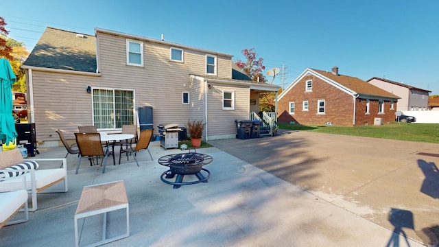 rear view of property featuring a patio area and an outdoor fire pit