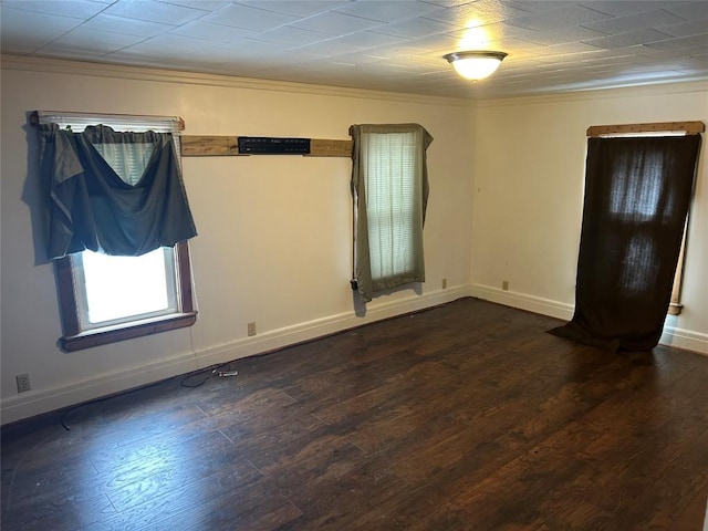 empty room featuring baseboards, dark wood-type flooring, and ornamental molding